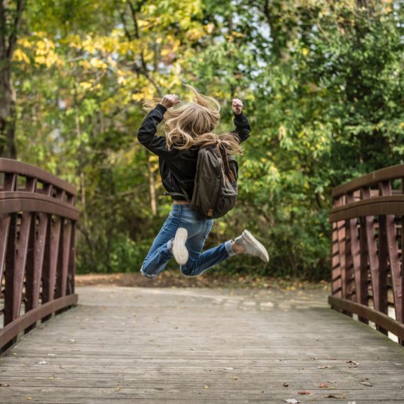 Una bambina fa salti di gioia su un ponte