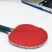 Un ordinateur portable et une raquette de ping-pong sur une table.