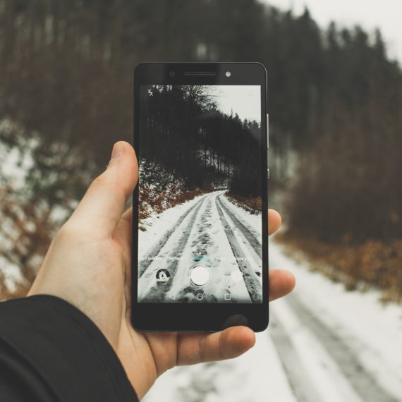 Un uomo fotografa una sentiero invernale con il suo smartphone.