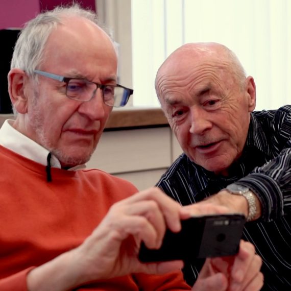 Peter Ritter (links) lässt sich von einem weiteren Kursteilnehmer etwas am Handy zeigen.