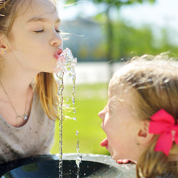 Due ragazze bevono da una fontana.