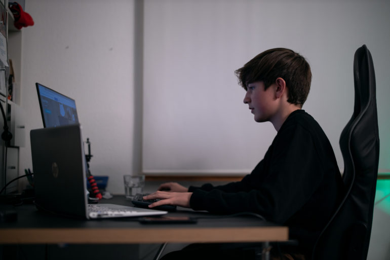 Jakob è seduto al computer e gioca a jass online.