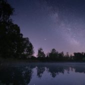 Sternenhimmel, der sich in einem See spiegelt.